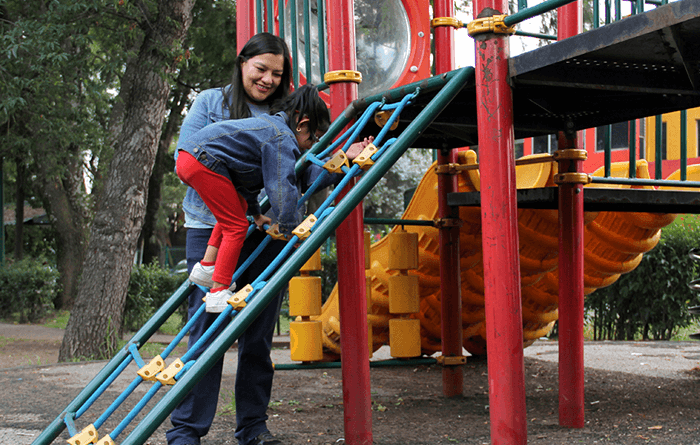 Mother playing with daughter on the playground.